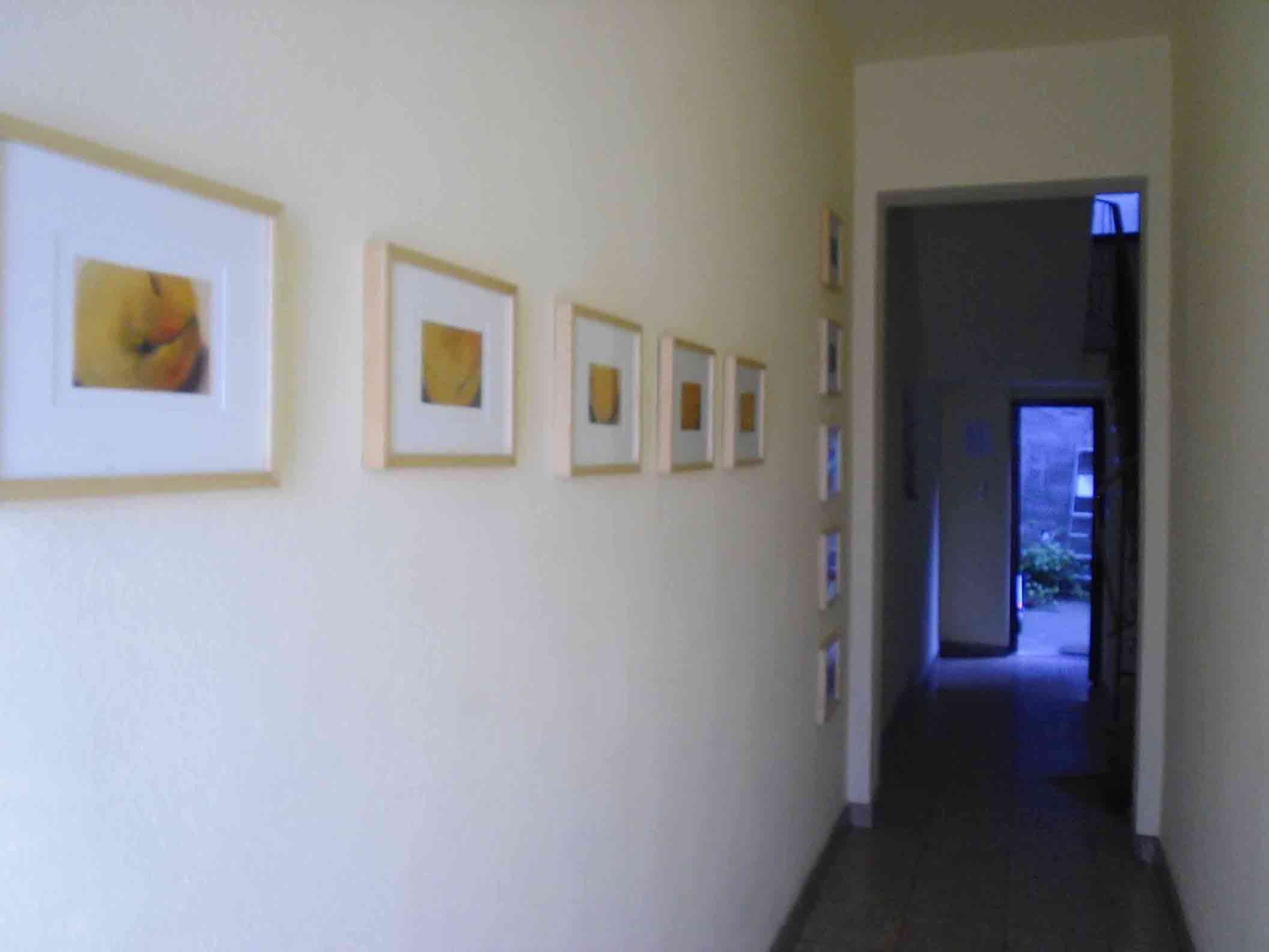 Ein paar von Peters Pastellen; eine waagerechte Reihe von 5 orangenen Pastellen, dahinter eine senkrechte Reihe von 5 roten Pastellen an der Wand zum Eingangsflur des Hauses